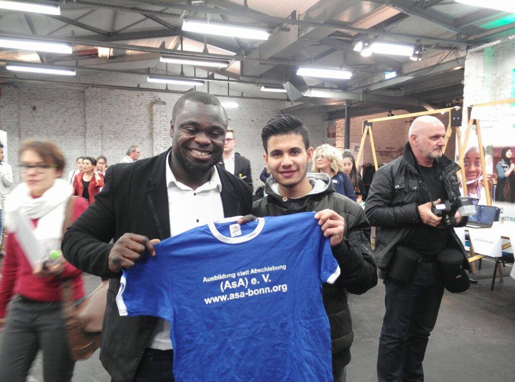 Roni Hussain aus Syrien, 17 Jahre, überreicht unser ASA-Tshirt an Gerald Asamoah, der auf Schalke immer nur kurz „Asa“ gerufen wurde.